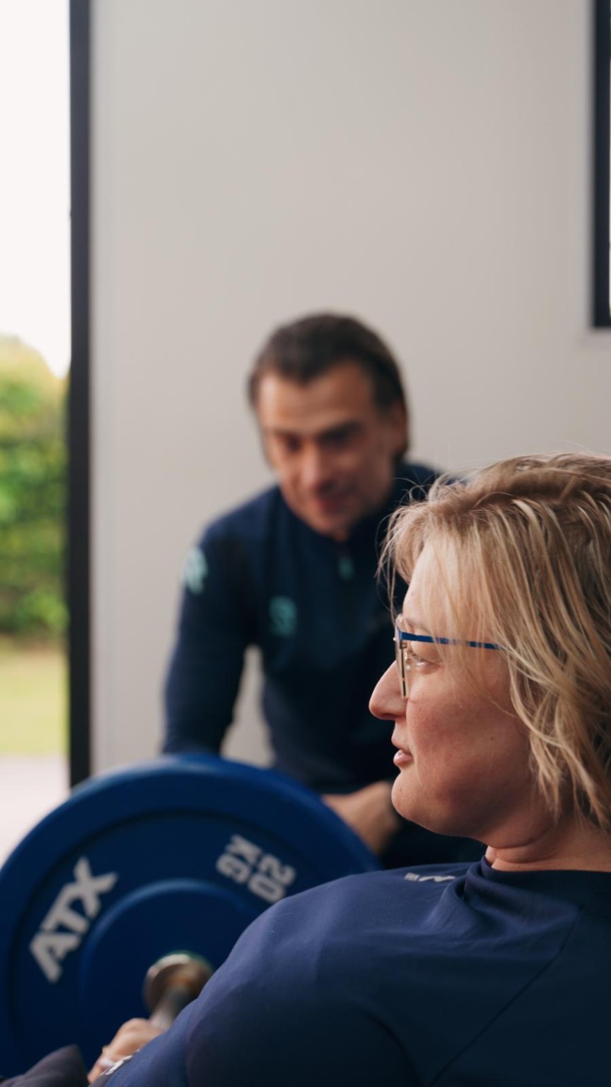 Ronnie begeleidt een klant bij krachttraining in De Sporttuin